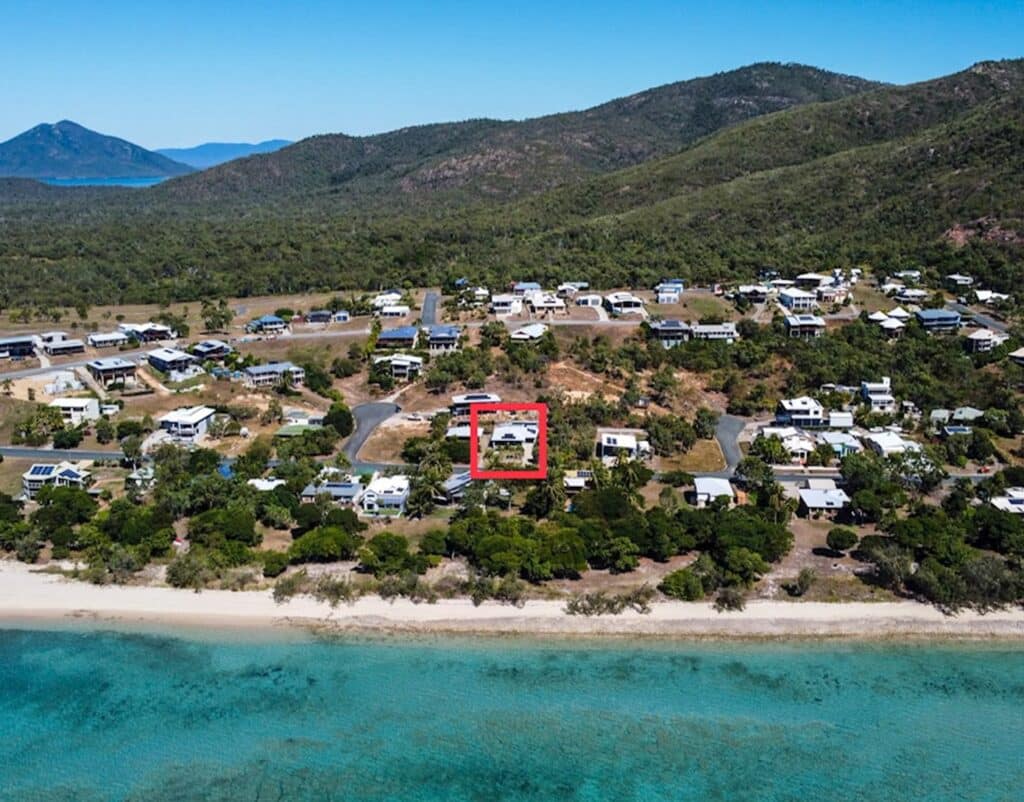 Aerial drone view of beachfront holiday homes and coastal properties in Hideaway Bay, Queensland.