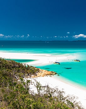 Scenic lookout view of luxury boats anchored in a crystal-clear turquoise bay in the Whitsunday Islands